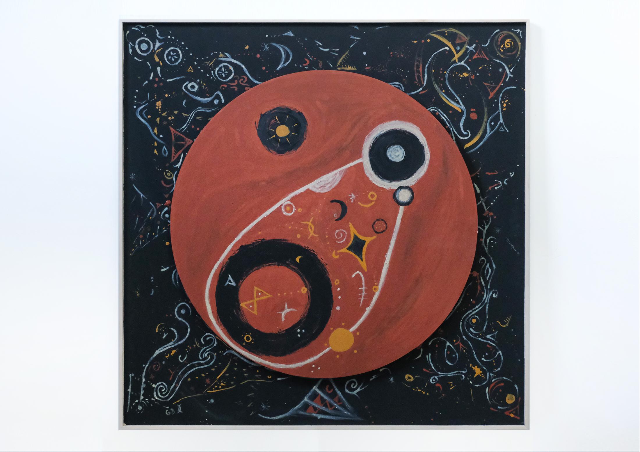 A square painting on a white wall. A large terracotta-red circle floats on a black ground, marked with white, yellow and pale blue symbols — spirals, crescents, stars and small rings.