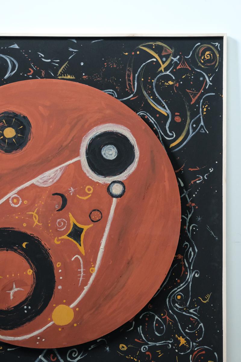 The painting seen at an angle against a white wall, the terracotta circle standing proud of the black square behind it.