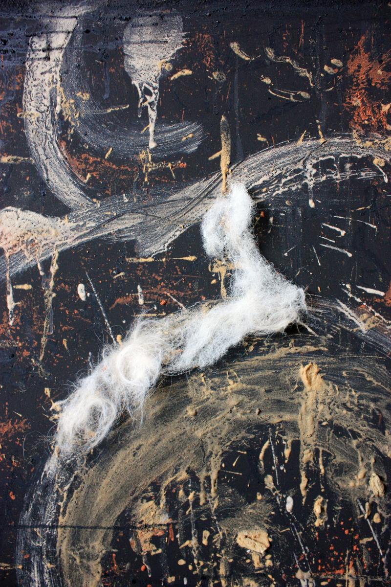 A close view of a painted surface: white and cream marks and a length of raw fleece pressed into a black ground scattered with ochre and red pigment.